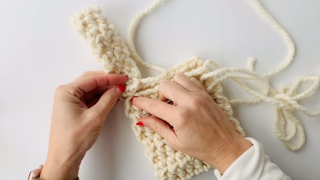 Seaming handle on crochet bag.